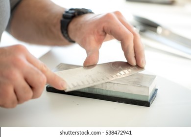 Man Sharpening Knife In Domestic Kitchen