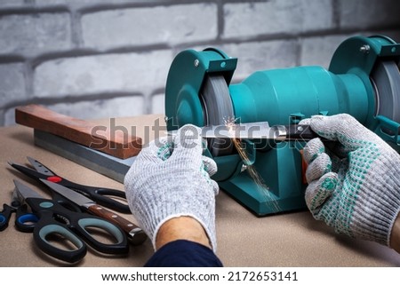 Man sharpening the knife with a electric sharpener. Small business.