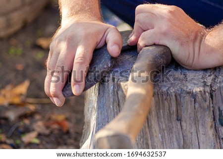 A man sharpens an axe with a whetstone. Weapon.