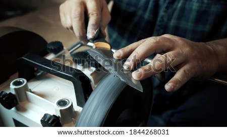 Man sharpens knives on a grinder. Close up hand
