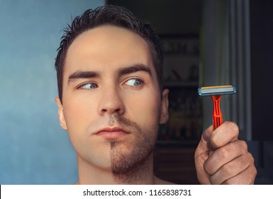 A Man Shaves His Face Without Cream Or Foam, Experiencing Pain And Suffering. Half Face Shaved Half Overgrown With A Thick Beard.