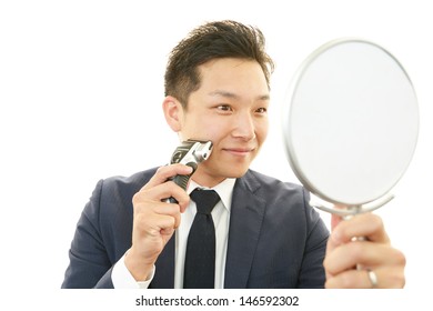 A Man Shaving With Electric Razor