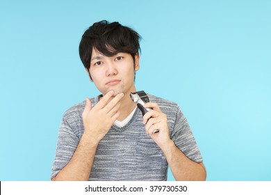 A Man Shaving With Electric Razor