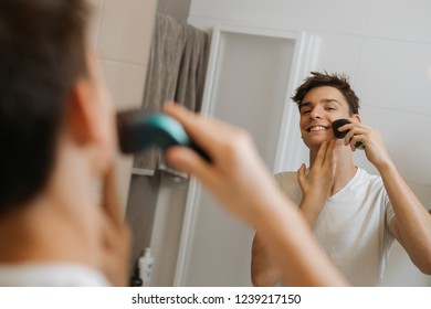 Man Shaving With Electric Razor In His Bathroom