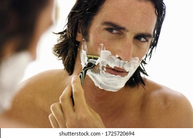 Man Shaving Face In Mirror