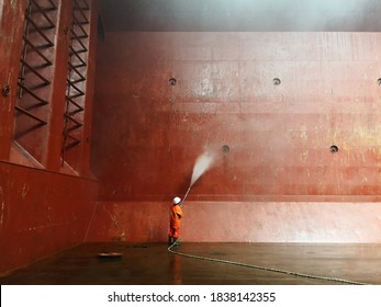 Man Or A Ship Crew Is Using High Pressure Washer Or Water Jet To Wash Cargo Hold On A Bulk Carrier