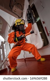 A man in ship's fire outfit on board a vessel opening door - Shutterstock ID 1696369288