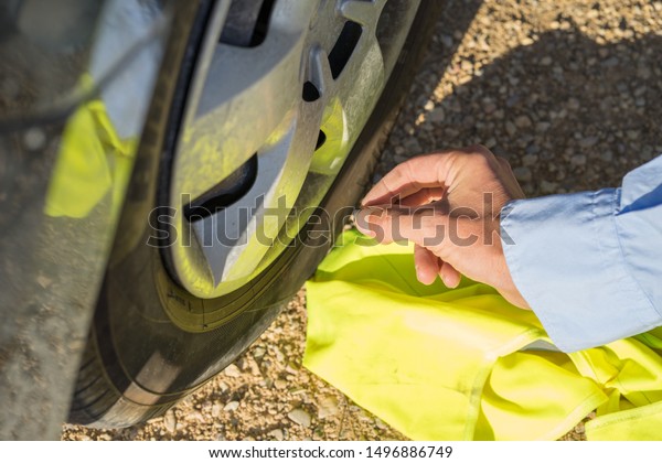 man with\
shirt fixing car Wheel with yellow\
vest