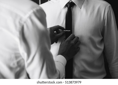 A man in a shirt is helped with a tie