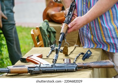 A Man In A Shirt Is Holding A Loaded Kalashnikov Assault Rifle. Exhibition Of Weapons For The Russian Army. A Military Man With A Gun In His Hands.