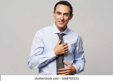 A Man In A Shirt Straightens A Tie Around His Neck