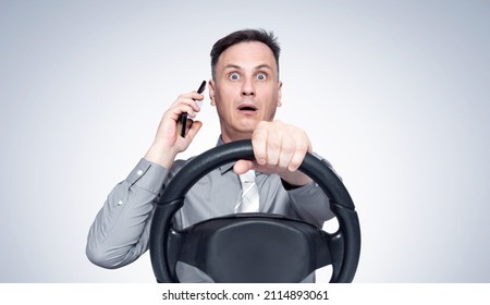 Man In Shirt And Tie Talking On The Phone While Driving, Front View On Light Background.