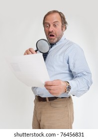  Man with a shocked expression analyzing a document through a magnifying glass