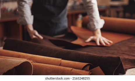 Man shoemaker hold different rolls natural leather brown, working with textile in workshop. - Powered by Shutterstock