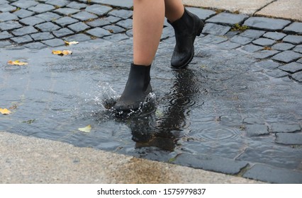 A man in shoes walking on the sidewalk and puddles