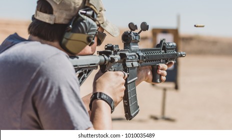 Man shooting rifle on desert range medium shot shell ejecting 