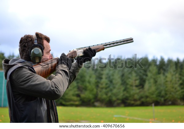 man shooting\
shotguns at clay pigeon\
outdoors
