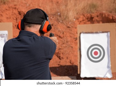 Man Shooting At A Target On An Outdoor Shooting Range, Focus On Gun