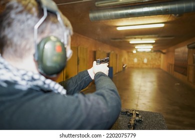 A Man Shoots In A Shooting Range From A Pistol With A Laser Sight At Targets.