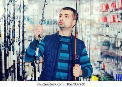 Man Shopper Choosing Ocean Fishing Rod In The Fishing Store
