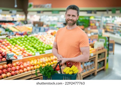 Man with shopping basket full of vegetables and fruits. Middle aged millennial man in a food store. Supermarket shopping and grocery shop concept. Man man 40s with shopping basket. - Powered by Shutterstock