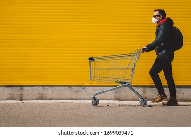 Man with with a shopping cart in front of a store, wearing a mask during a coronavirus pandemic / Covid-19.