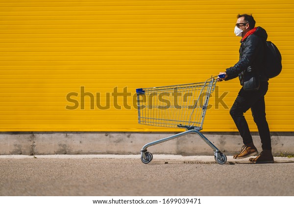 Man with with a
shopping cart in front of a store, wearing a mask during a
coronavirus pandemic /
Covid-19.