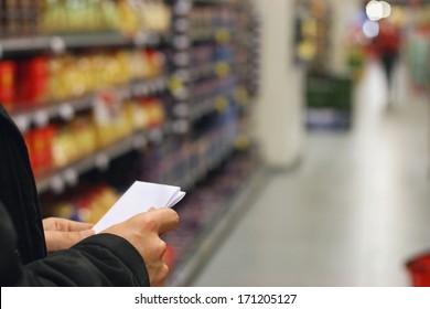 A Man With Shopping List, Grocery Store Shelves And Products In Background