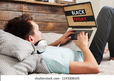 Man shopping on Black Friday special by the internet with a laptop computer, while lying down on the bed at home.