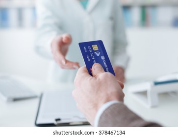 Man Shopping In The Pharmacy, He Is Giving The Credit Card To The Cashier