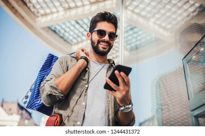 Man in shopping. Smiling man with shopping bags enjoying in shopping. Consumerism, shopping, lifestyle concept - Powered by Shutterstock