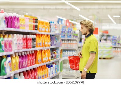 Man Shopping In Supermarket Reading Product Information.(diapers,detergent)