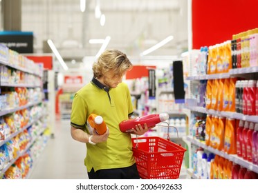 Man Shopping In Supermarket Reading Product Information.(diapers,detergent)