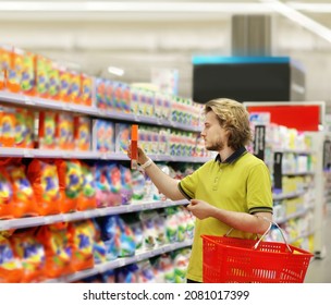 Man Shopping In Supermarket Reading Product Information.(diapers,detergent)