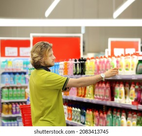 Man Shopping In Supermarket Reading Product Information.(diapers,detergent)