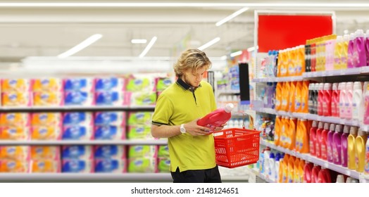 Man Shopping In Supermarket Reading Product Information.(diapers,detergent)