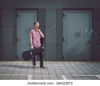 Man In Short Sleeve Shirt Holding Guitar Case In The Street