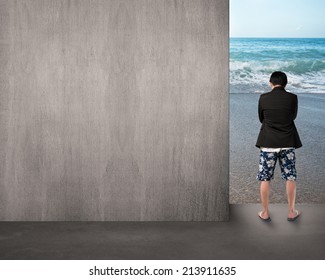 Man In Shorts Thinking And Standing On Beach Entrance With Empty Wall