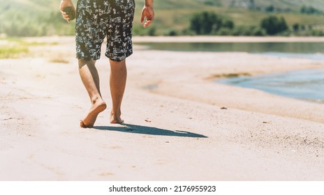 Man In Shorts Walking On The Sandy Beach.