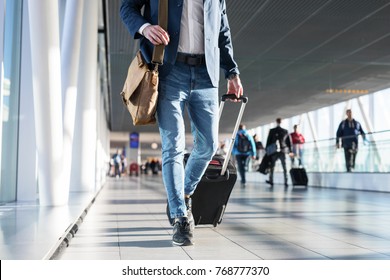 Man with shoulder bag and hand luggage walking in airport terminal
