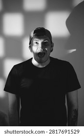 Man with shouting expression looking at camera. Portrait of young caucasian male wearing baseball cap with dramatic shadow lighting. Artistic photography of human emotion and reaction.