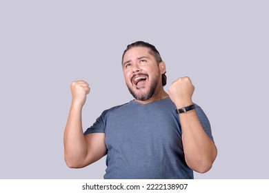 A man shouts in elation. Overjoyed man celebrating victory, pumping his fists. Isolated on a gray background. - Shutterstock ID 2222138907