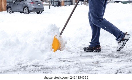 Man shoveling snow off of his driveway after a winter storm in Canada. Man with snow shovel cleans sidewalks in winter. Winter time