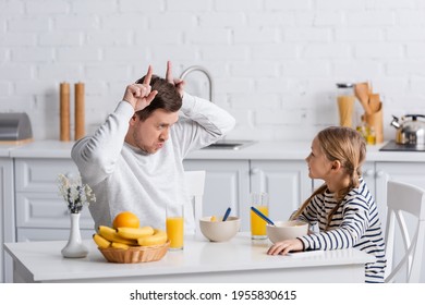 Man Showing Bull Horn Gesture While Having Fun During Breakfast With Daughter