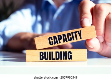 Man showing Capacity Building text on wooden blocks. - Shutterstock ID 2037980549
