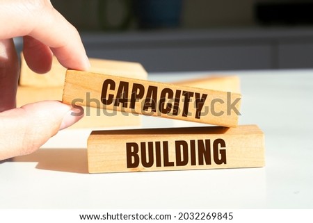 Man showing Capacity Building text on wooden blocks.