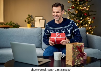 Man Showing Christmas Present While In Video Call With On Laptop