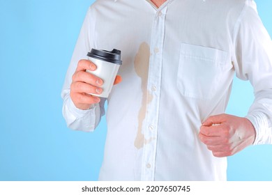 A Man Showing A Dirty Coffee Stain On Shirt A Blue Background. Spoiled Clothes. Dirty Coffee Stain On Clothes. Daily Life Stain Concept. High Quality Photo