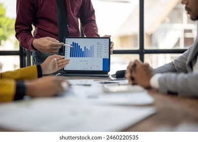 A man is showing a graph to a group of people. The graph shows a downward trend, which could indicate a decrease in sales or a decline in performance - Powered by Shutterstock - Get 15% off with code: PIKWIZARD15