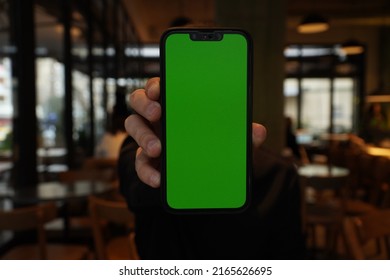 Man Showing Green Screen Mobile Phone At Cafe Vertically